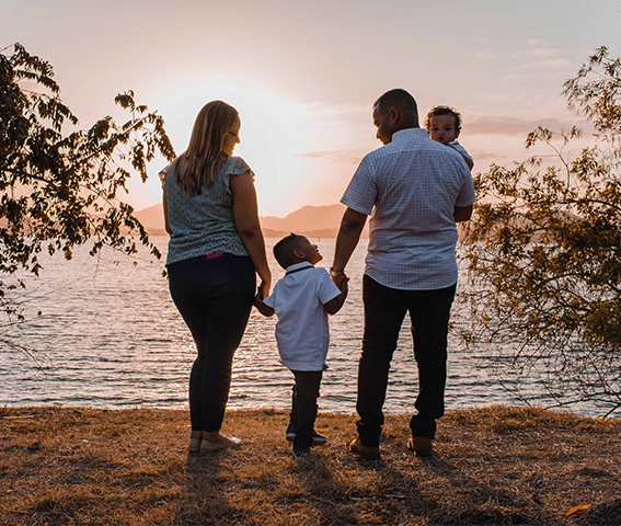 Family of four standing in front of a lake.